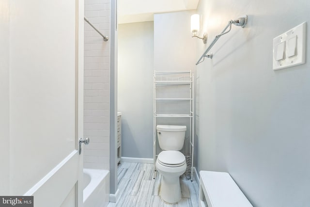 bathroom featuring baseboards, washtub / shower combination, and toilet