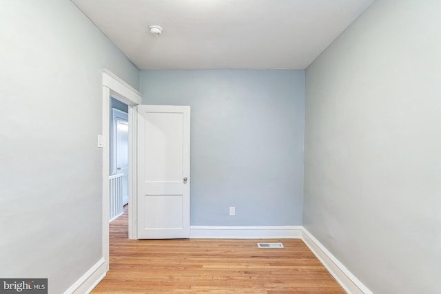 unfurnished room featuring light wood-style flooring, visible vents, and baseboards