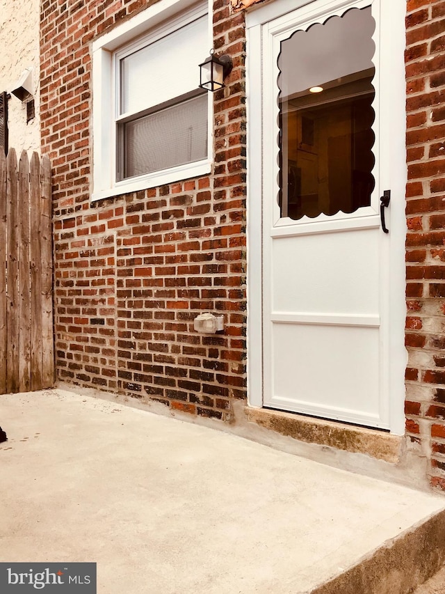 property entrance featuring brick siding and fence