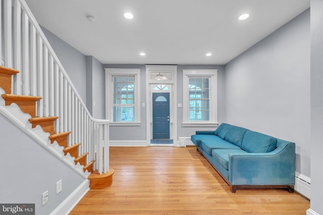 foyer featuring a baseboard radiator, stairs, light wood-style flooring, baseboards, and recessed lighting
