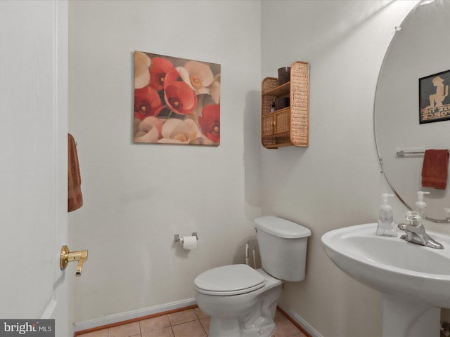 half bathroom featuring tile patterned floors, a sink, toilet, and baseboards