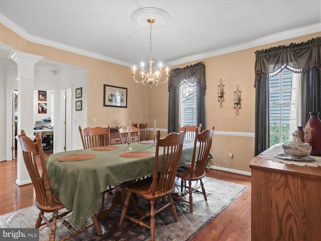 dining space featuring crown molding, baseboards, decorative columns, wood finished floors, and a notable chandelier