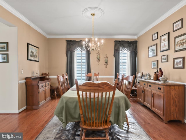 dining space featuring ornamental molding, a notable chandelier, baseboards, and light wood-type flooring
