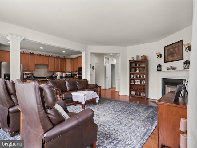 living room featuring recessed lighting, ornate columns, wood finished floors, and a glass covered fireplace