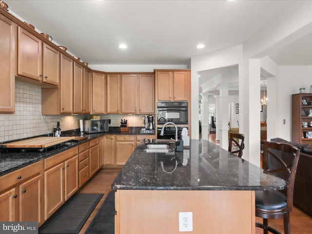 kitchen with black appliances, a kitchen island with sink, dark wood-style floors, and a sink