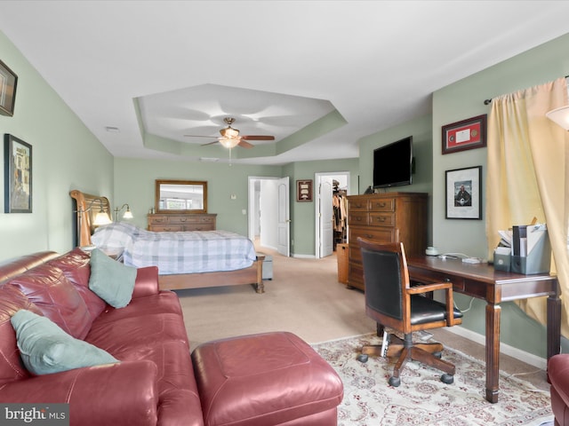 bedroom with carpet flooring, ceiling fan, a tray ceiling, baseboards, and a spacious closet