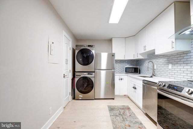 203 Yoakum Pkwy Unit 1520, Alexandria, VA 22304 - kitchen with wall chimney range hood, a sink, stainless steel appliances, stacked washer / dryer, and backsplash