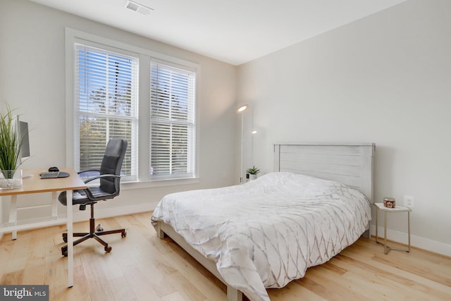 bedroom with baseboards, wood finished floors, and visible vents