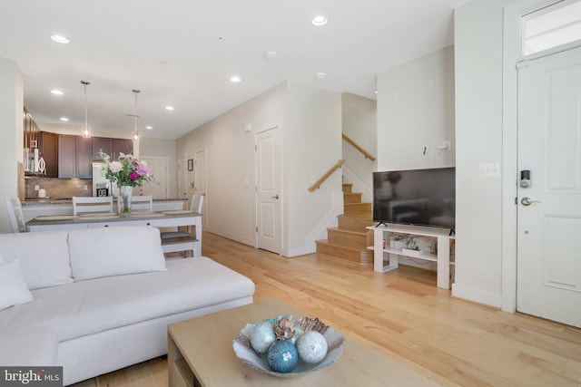 living room with stairs, recessed lighting, baseboards, and light wood-style floors