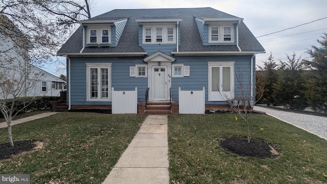 view of front facade with roof with shingles and a front lawn
