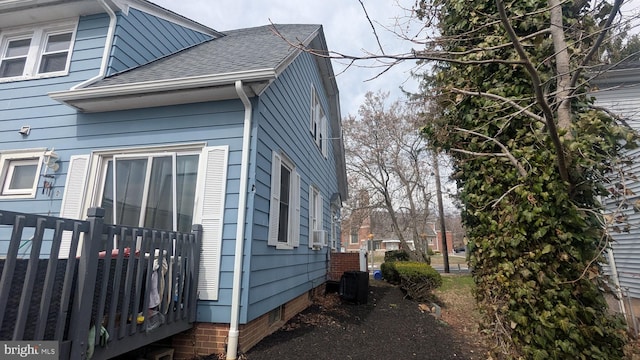 view of side of home with roof with shingles