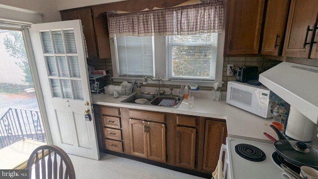 kitchen with white appliances, light countertops, a sink, and backsplash