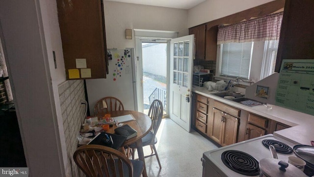 kitchen featuring white appliances, light countertops, a sink, and decorative backsplash