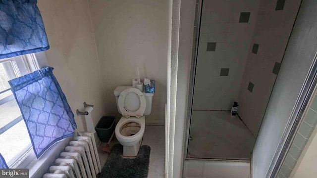 full bathroom with toilet, radiator, and a shower with door