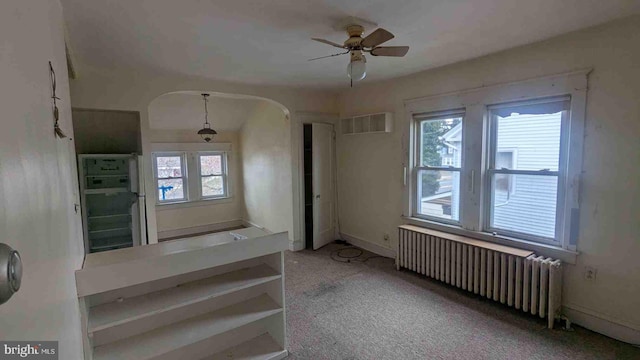 staircase with visible vents, arched walkways, ceiling fan, carpet floors, and radiator heating unit