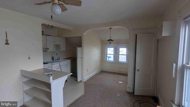 kitchen featuring baseboards, arched walkways, a ceiling fan, white appliances, and white cabinetry