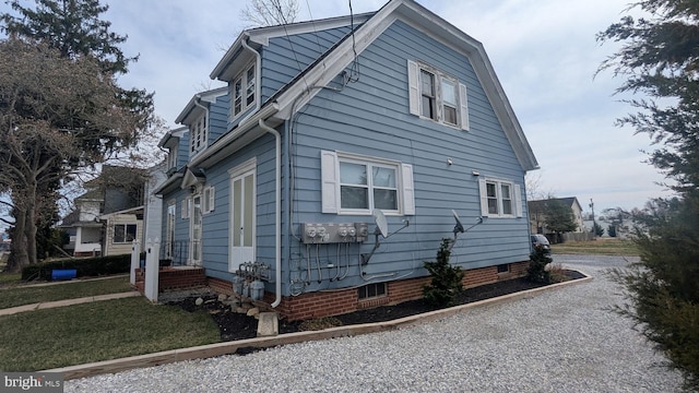 view of side of property featuring a gambrel roof and driveway