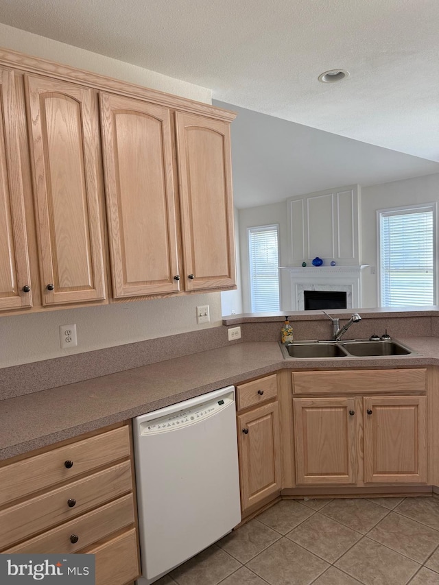 kitchen featuring plenty of natural light, white dishwasher, a sink, and light brown cabinets