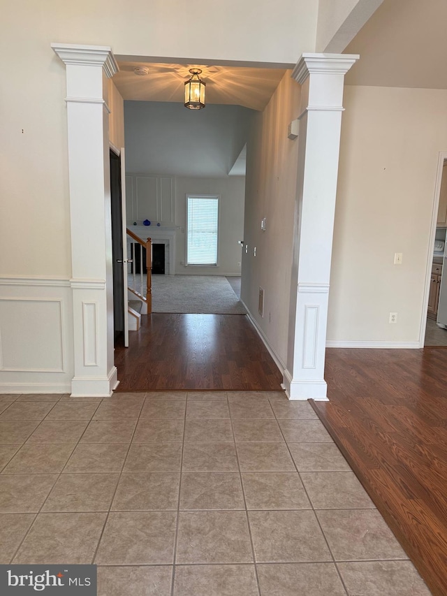 hallway featuring tile patterned floors and decorative columns