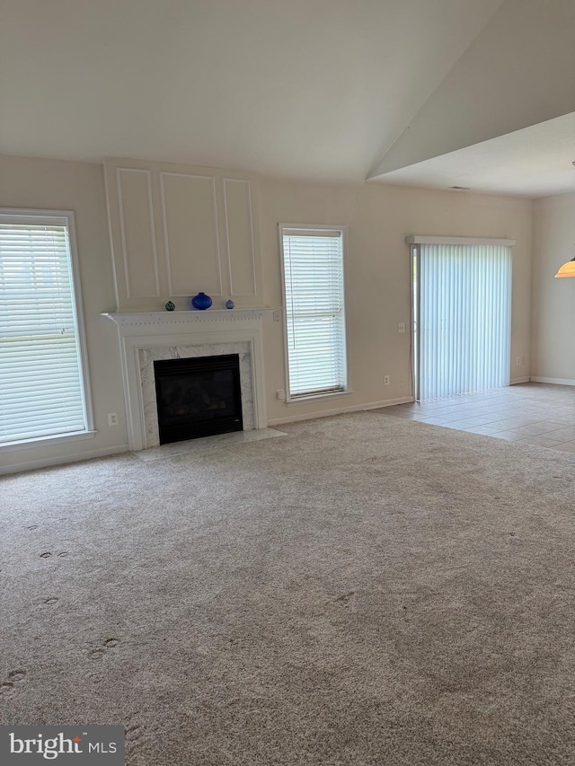 unfurnished living room featuring plenty of natural light, carpet flooring, and a fireplace