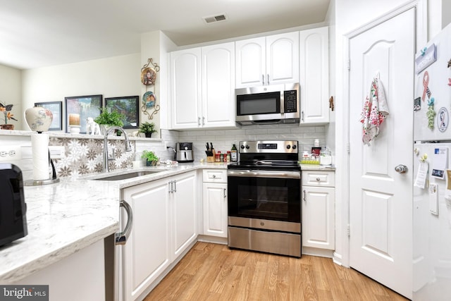 400 Symphony Cir Unit 351, Cockeysville, MD 21030 - kitchen featuring tasteful backsplash, a sink, light wood finished floors, appliances with stainless steel finishes, and visible vents