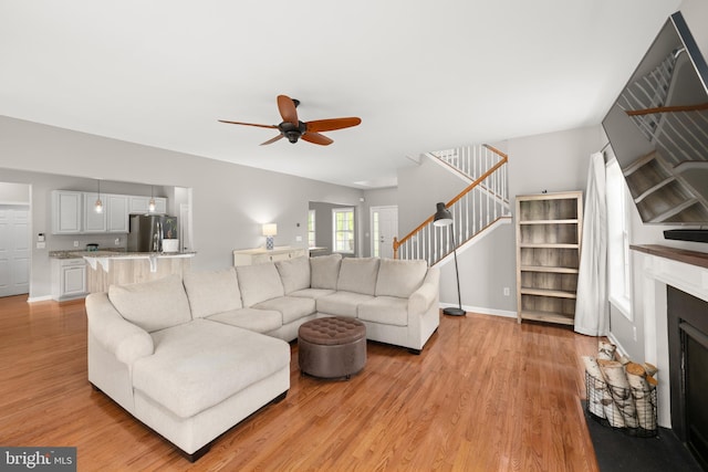 16260 Edgewater Dr, Milton, DE 19968 - living room featuring light wood finished floors, stairway, a ceiling fan, baseboards, and a fireplace