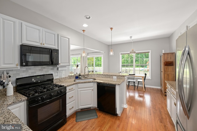 16260 Edgewater Dr, Milton, DE 19968 - kitchen with black appliances, a sink, a peninsula, white cabinetry, and light wood-style floors