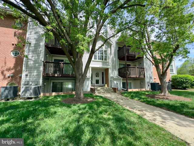 view of front of property featuring central air condition unit, a front yard, and a balcony