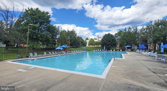 pool featuring a lawn, fence, and a patio area