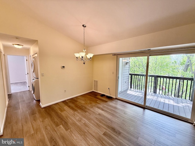 unfurnished dining area with baseboards, wood finished floors, stacked washing maching and dryer, and visible vents
