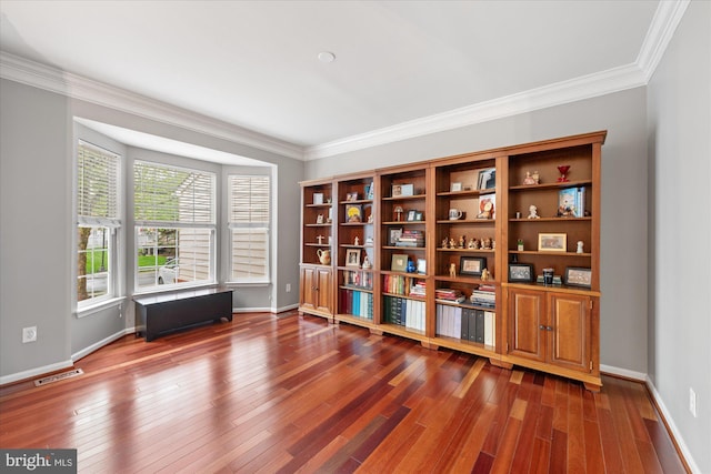 unfurnished room featuring wood finished floors, visible vents, ornamental molding, and baseboards