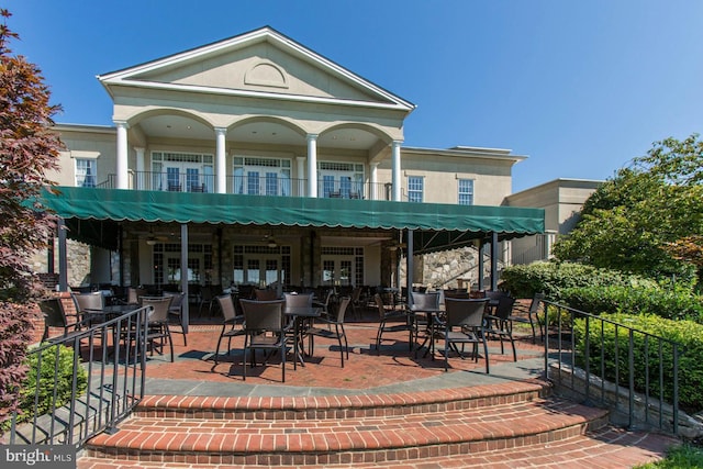 view of patio / terrace featuring french doors, fence, outdoor dining area, and a balcony