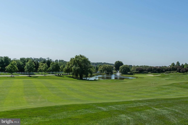 surrounding community with a water view, a yard, and golf course view