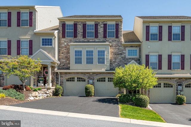 multi unit property featuring stucco siding, driveway, and stone siding