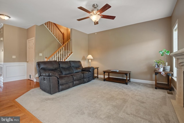 living room with stairway, a ceiling fan, wood finished floors, and a premium fireplace