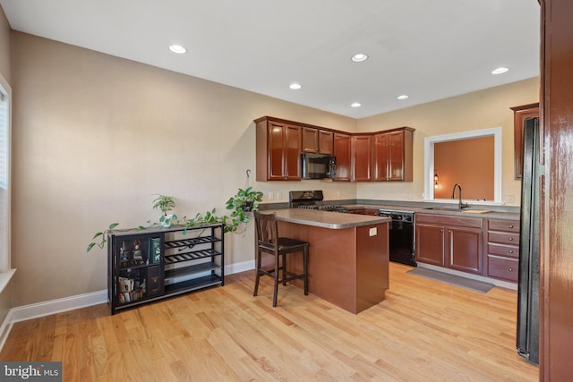 kitchen with a sink, light wood-style floors, a peninsula, recessed lighting, and black appliances