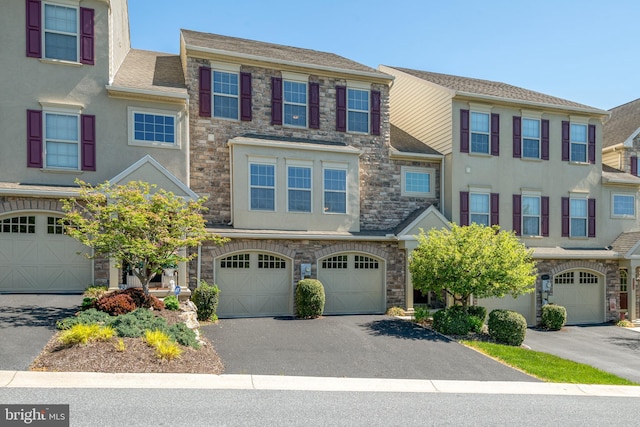 view of property featuring a garage, stucco siding, driveway, and stone siding