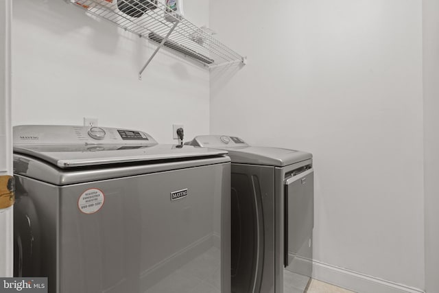 laundry room with washing machine and clothes dryer, light tile patterned flooring, laundry area, and baseboards