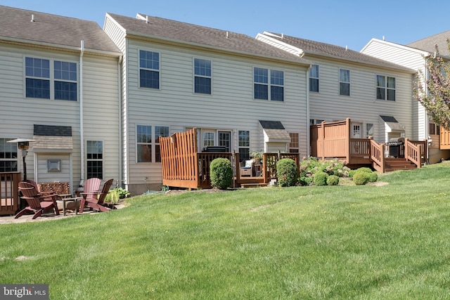 rear view of house featuring a lawn, a fire pit, and a wooden deck