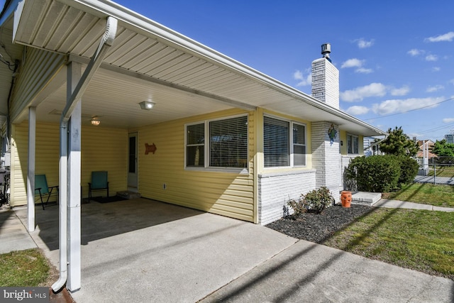 9007 Coastal Hwy, Ocean City, MD 21842 - exterior space with fence, a chimney, an attached carport, and brick siding