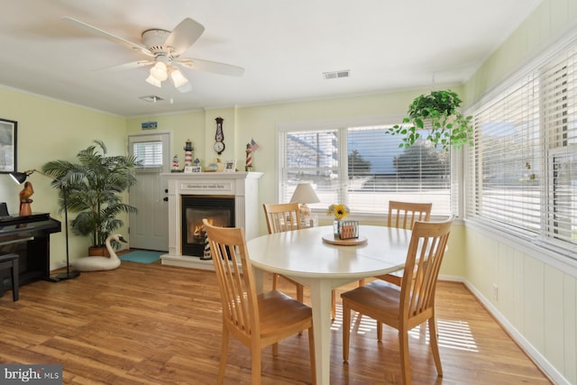 9007 Coastal Hwy, Ocean City, MD 21842 - dining space featuring visible vents, ornamental molding, a glass covered fireplace, light wood-style flooring, and ceiling fan