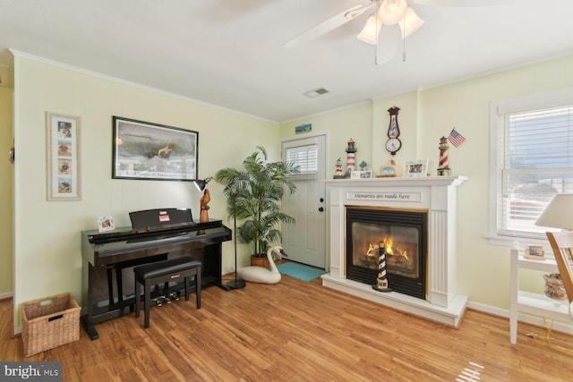 9007 Coastal Hwy, Ocean City, MD 21842 - living area with a ceiling fan, wood finished floors, a glass covered fireplace, ornamental molding, and visible vents