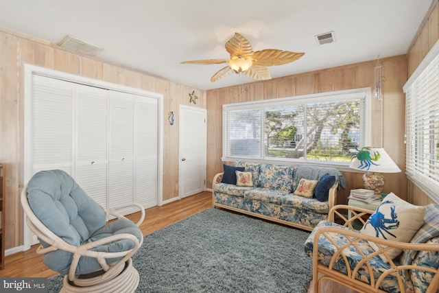 9007 Coastal Hwy, Ocean City, MD 21842 - living room with ceiling fan, visible vents, wood finished floors, and wooden walls