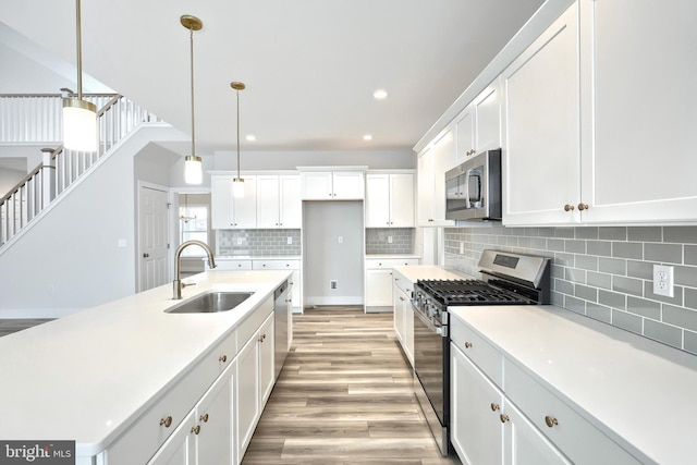 146 Wyndale Dr, Ephrata, PA 17522 - kitchen with white cabinets, stainless steel appliances, a sink, light wood-style flooring, and tasteful backsplash