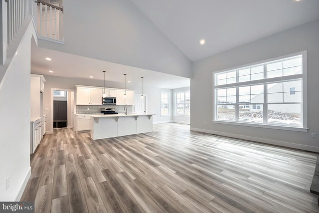 146 Wyndale Dr, Ephrata, PA 17522 - unfurnished living room with high vaulted ceiling, baseboards, light wood-style floors, and recessed lighting