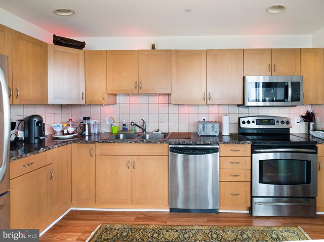901 N Penn St Unit P506, Philadelphia, PA 19123 - kitchen featuring light wood-style flooring, dark stone counters, a sink, and stainless steel appliances