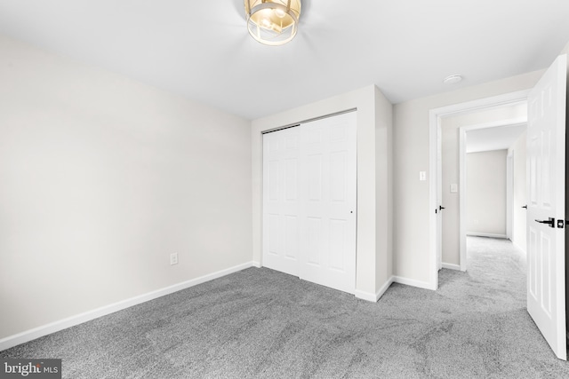unfurnished bedroom featuring carpet, baseboards, and a closet