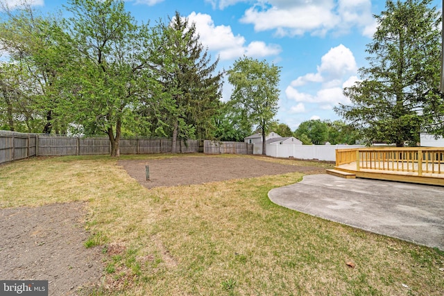 view of yard featuring a patio, a wooden deck, and a fenced backyard