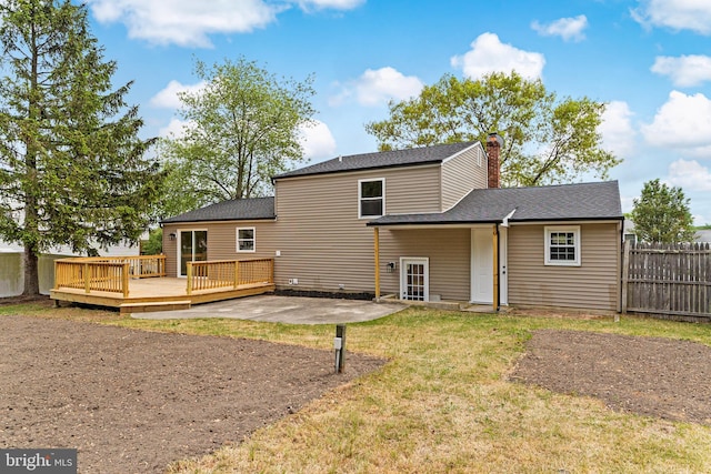 rear view of property featuring a patio area, fence, a deck, a yard, and a chimney