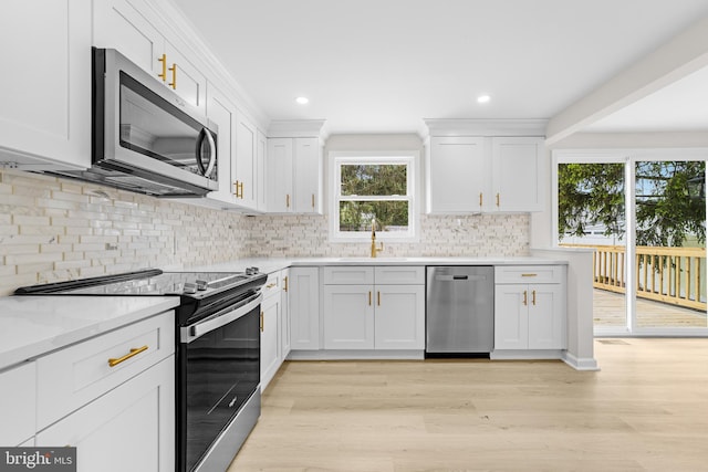 kitchen featuring light wood finished floors, white cabinets, a healthy amount of sunlight, and appliances with stainless steel finishes